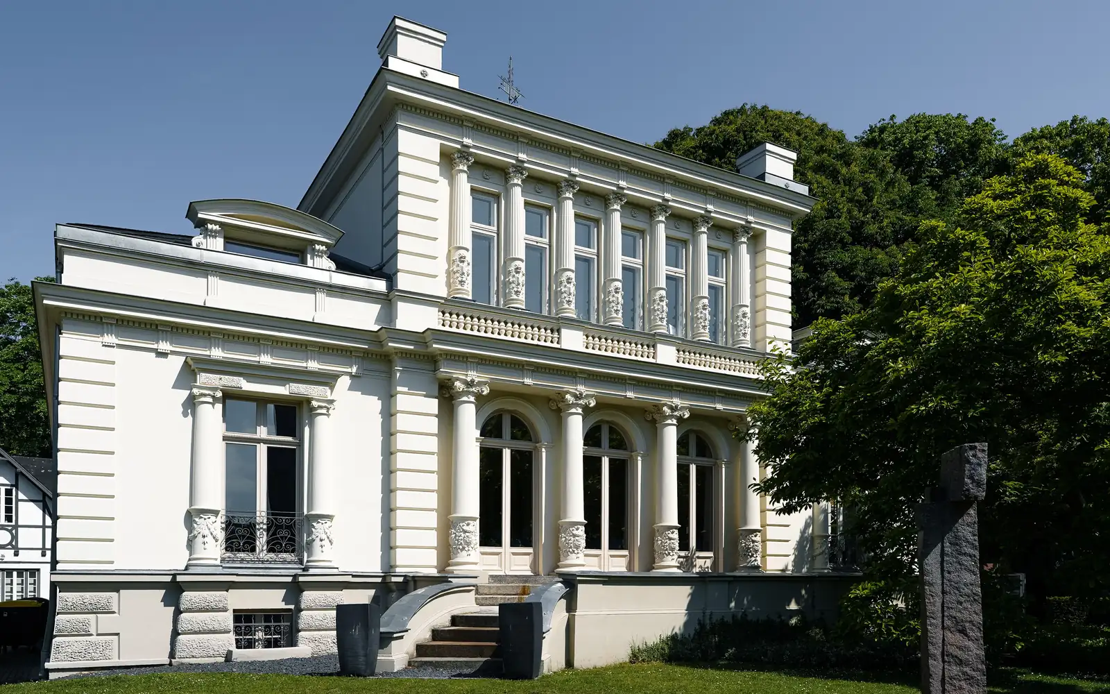 Weiße klassizistische Villa mit Säulen, Balustrade und Freitreppe hinter einer Rasenfläche (Barmbek-Nord, Hamburg)