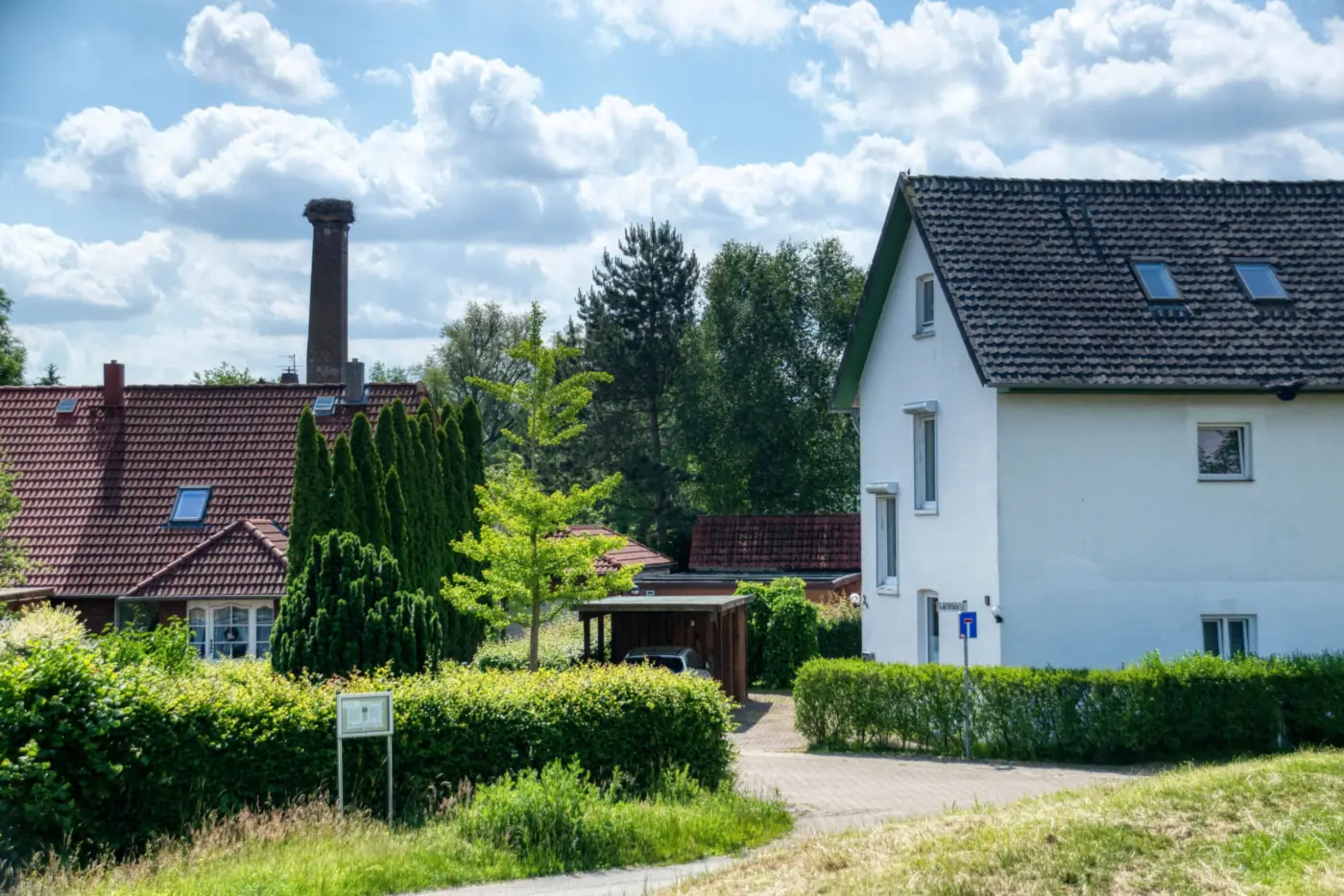 Weißes Wohnhaus mit dunklem Satteldach und Dachfenstern hinter Hecken, daneben ein Carport (Dohna, Landkreis Sächsische Schweiz)
