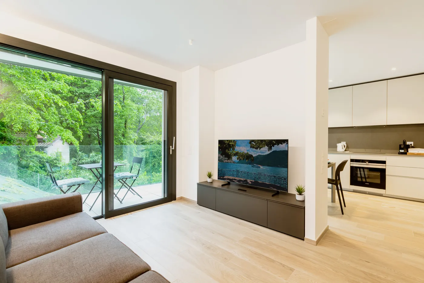 Offener Wohnbereich mit Küchenzeile und raumhoher Glastür zum Balkon ins Grüne (Westheim, Landkreis Germersheim)