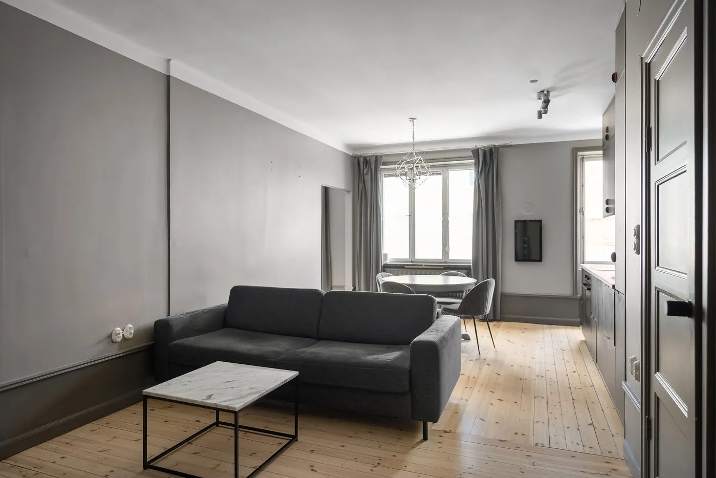 Wohnzimmer mit dunklem Sofa, Dielenboden und rundem Esstisch vor hohen Fenstern (Neuendorf, Landkreis Main-Spessart)