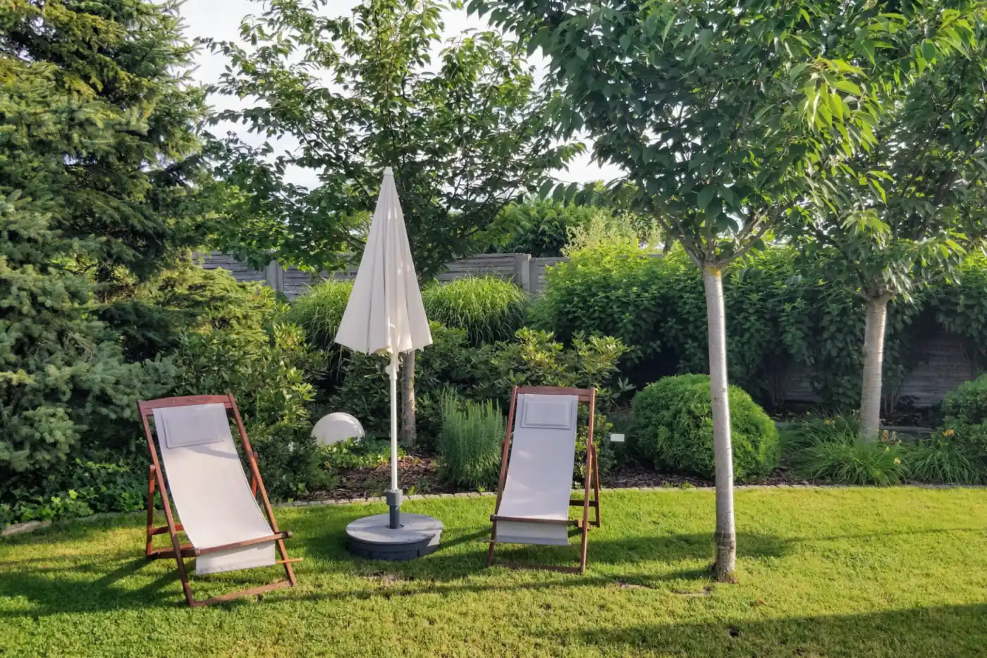 Gepflegter Garten mit Rasen, zwei Liegestühlen, Sonnenschirm und Hecken (Hillesheim, Vulkaneifel)